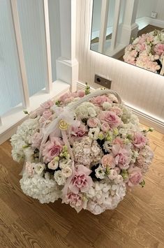 a bouquet of flowers sitting on top of a wooden floor next to a mirror in a room