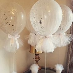 three white balloons with bows and tulle are on display in front of a mirror