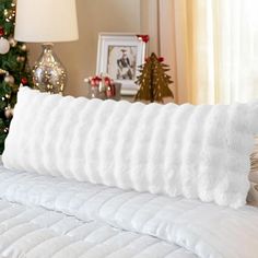 a white pillow on top of a bed next to a christmas tree