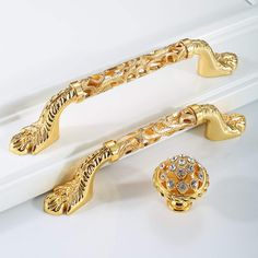 two gold colored handles and knobs on a white surface with crystal stones in the center