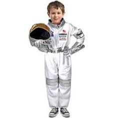 a young boy dressed in an astronaut suit and holding a helmet on his chest with both hands