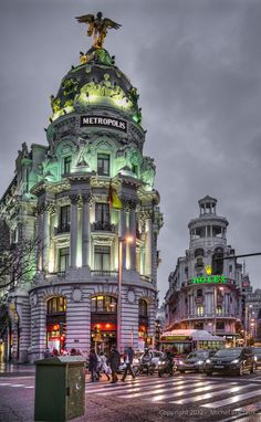 the metropolitan building is lit up with green and white lights on it's roof