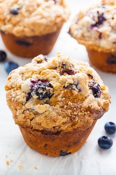 blueberry muffins with crumbs on a white surface