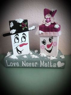 two snowmen are sitting on top of a book with love never melts written on it