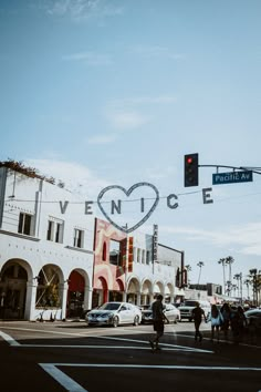 people crossing the street at an intersection in front of a building with a heart on it