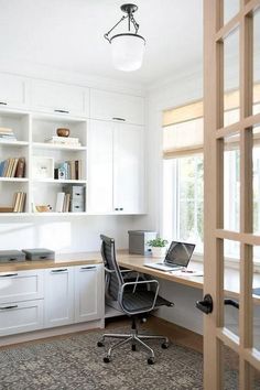 a home office with white cabinets and shelves