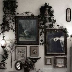 a living room filled with lots of pictures and plants on the wall next to a couch