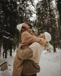 two people are playing in the snow with one holding the other's head and looking up