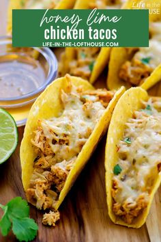 two chicken tacos on a cutting board with cilantro and lime wedges