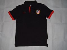 the shirt is black and red with a white stripe around the collar, and has an emblem on the chest