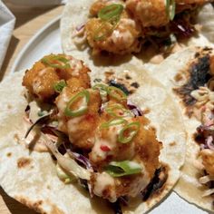 three tacos on a white plate topped with meat and veggie toppings