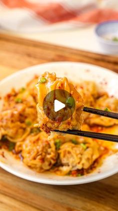 a white plate topped with food and chopsticks on top of a wooden table