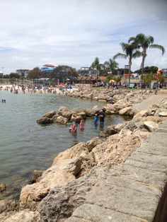 people are swimming in the water near some rocks