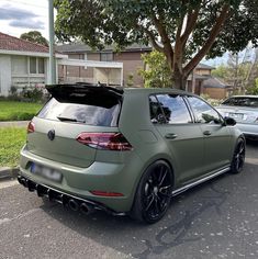 the rear end of a green volkswagen golf gtr parked in front of a house