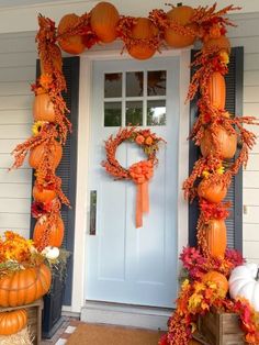 a front door decorated for fall with pumpkins and gourds