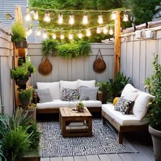 an outdoor living area with couches, tables and potted plants on the wall