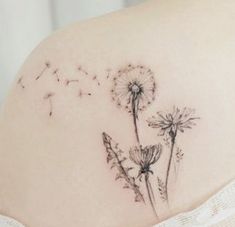 a woman's back with a dandelion tattoo on it