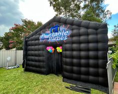 an inflatable party tent with balloons and streamers on the front lawn at a backyard party