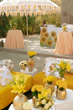 an outdoor event with yellow and white furniture, sunflowers and flowers on the tables