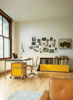 a living room with a couch, desk and bookshelf next to a window