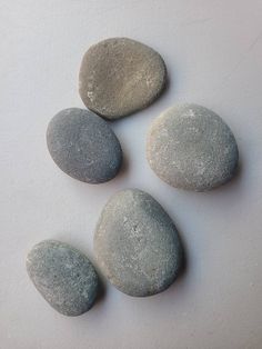 four rocks are arranged in the shape of three circles on a white surface, and one is gray