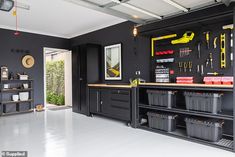 a garage with black cabinets and tools hanging on the wall