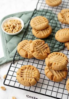 peanut butter cookies cooling on a wire rack next to a bowl of peanuts and a napkin