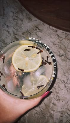 a person holding a glass with lemon slices in it and the words mood of life written on top