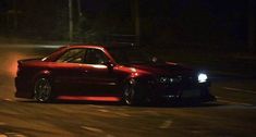 a red car driving down a street at night