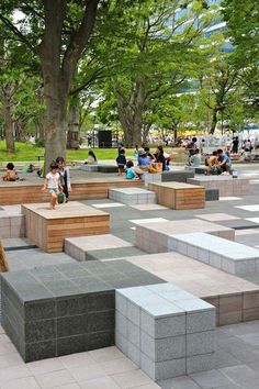 many people are sitting and walking around in the park with large blocks on each side