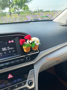 two crocheted flowers are placed in the center console of a car's dashboard