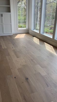 an empty room with wood floors and large windows