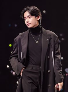 a male model in a black suit and turtle neck sweater