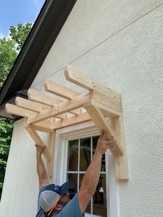 a man is working on a wooden structure in front of a window with his hands