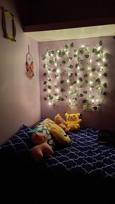 two stuffed animals sitting on top of a bed in a room with string lights hanging from the wall