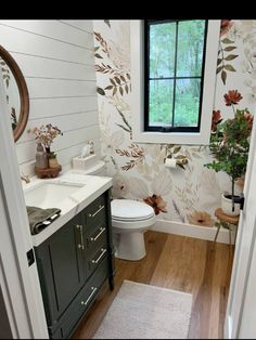 a bathroom with floral wallpaper and wooden floors