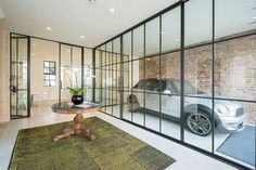 a living room filled with furniture and a car in the glass walled entryway to a home