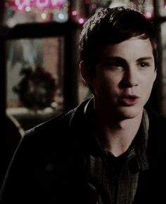 a young man standing in front of a window with christmas lights on the windowsill