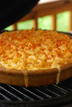 a pizza sitting on top of a grill covered in macaroni and cheesy