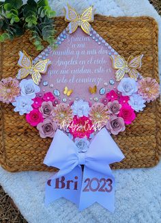 a graduation cap decorated with flowers and butterflies on a mat that reads, bri 205