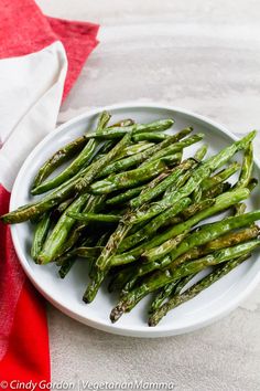 asparagus on a white plate next to a red napkin