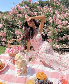 a woman sitting at a picnic table in front of pink flowers with her hands on her head