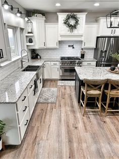 a kitchen with white cabinets and wood floors