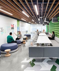 people are sitting at long tables in an office with green and white accents on the walls