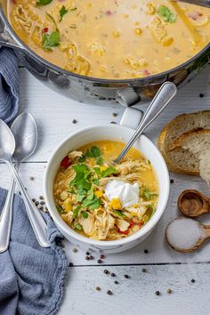 a bowl of soup next to some bread and spoons