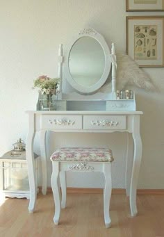 a white dressing table with a mirror and stool in front of it on a hard wood floor