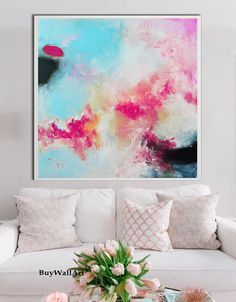 a living room with white couches and pink flowers on the coffee table in front of it