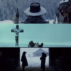 two people are standing in front of a cross and looking at the snow covered mountains