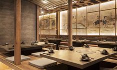 an empty restaurant with wooden tables and chairs in front of large paintings on the wall