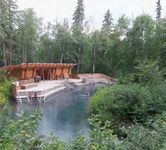 a body of water surrounded by trees and people swimming in the water with wooden rafts